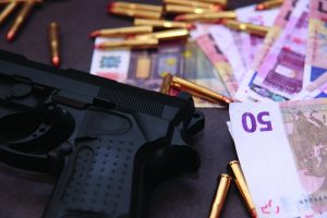 Image of gun, bullet casings, and international cash