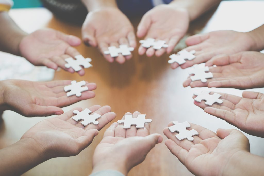 Many persons holding pieces of jigsaw puzzle, Teamwork, Success and strategy concept