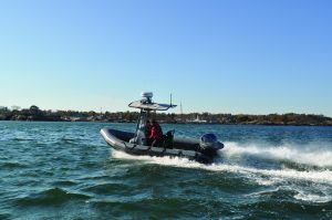 Rigid inflatable boat skimming across river.