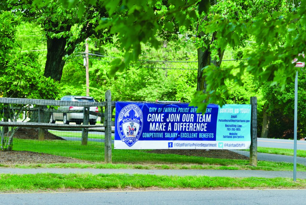 A banner hangs near the City of Fairfax Police Department headquarters seeking new police officer recruits to "Come Join Our Team Make A Difference".